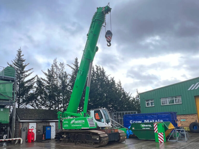 big green telescopic crawler crane with Emerson Cranes branding on it, on a construction site